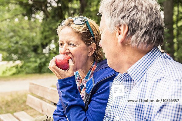 Paar sitzt im Freien  reife Frau isst Apfel