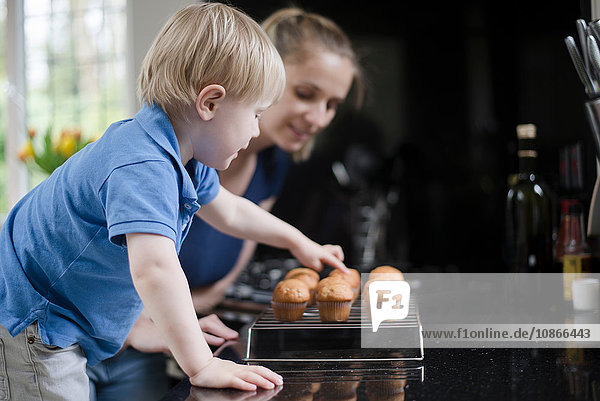 Mutter und Sohn warten auf frisch gebackene Muffins zum Abkühlen