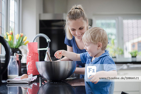 Mutter hilft Sohn beim Kuchenbacken  Sohn knackt Ei