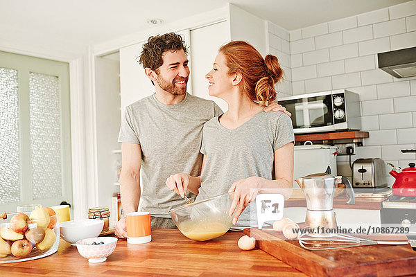 Mittelgroßes erwachsenes Paar verquirlt zum Frühstück Eier an der Küchentheke