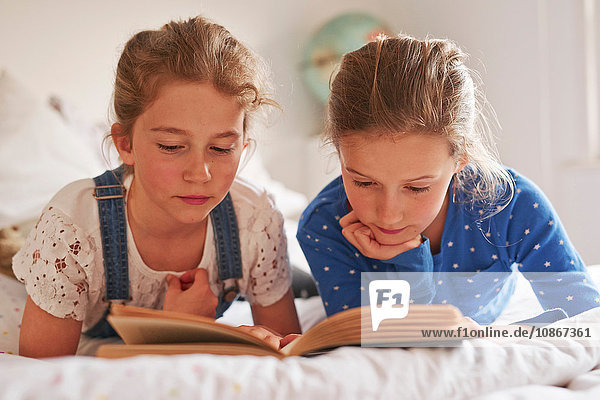 Zwei Schwestern liegen im Bett und lesen ein Buch