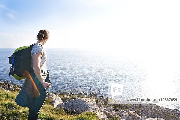 Wanderer mit Rucksack auf einer Klippe mit Blick auf den Ozean  Portland  UK
