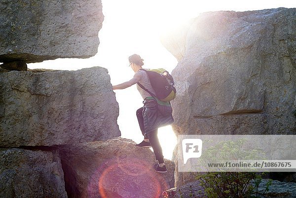 Seitenansicht einer Frau mit Rucksack beim Klettern an Felsen