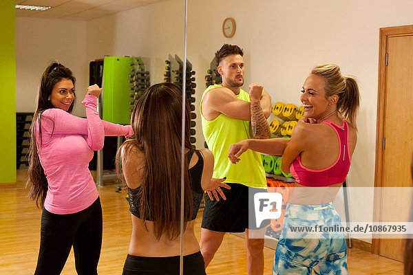Spiegelbild von Menschen im Fitnessstudio  die Armstreckübungen machen