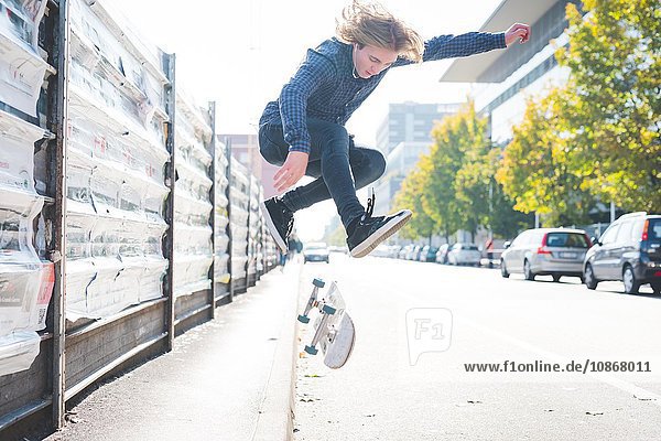 Junger männlicher Skateboardfahrer beim Skateboardspringen auf der Straße