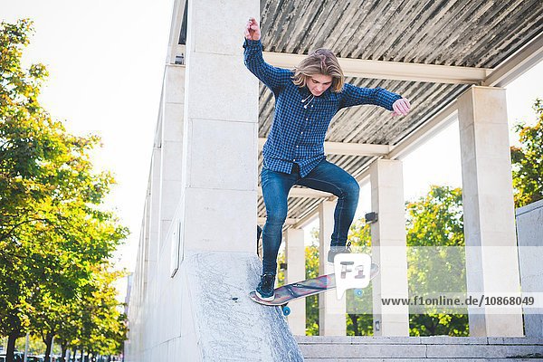 Junge männliche Skateboarder aus der Stadt  die Betonstruktur hinunterlaufen