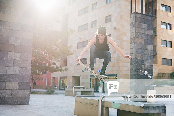 Junger Skateboardfahrer springt über den Sitz in der Stadthalle