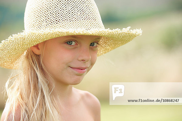 Porträt eines jungen Mädchens im Freien  das einen Strohhut trägt
