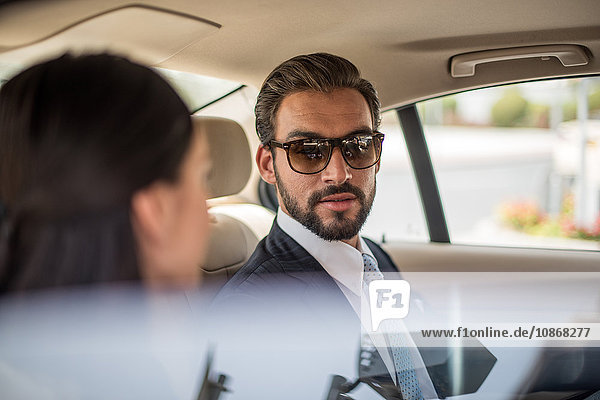 Young businessman and woman talking in car backseat  Dubai  United Arab Emirates