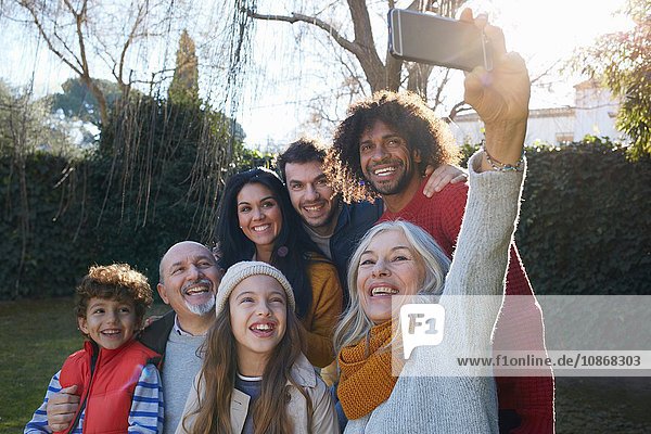 Multi generation family huddled together using smartphone to take selfie  smiling