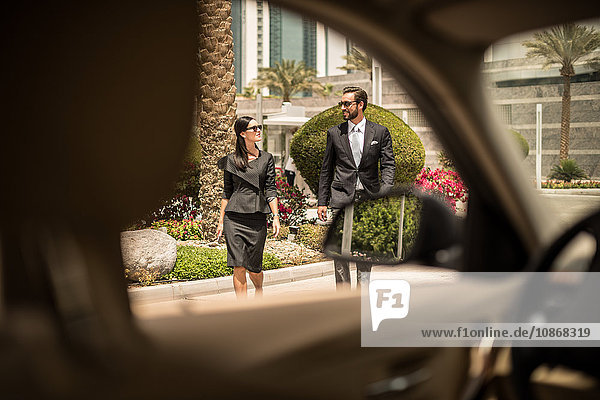 Autofensteransicht einer Geschäftsfrau und eines Mannes zu Fuß vor dem Hotel  Dubai  Vereinigte Arabische Emirate