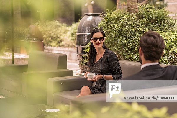 Geschäftsmann und -frau im Gespräch auf Hotelgartensofa  Dubai  Vereinigte Arabische Emirate