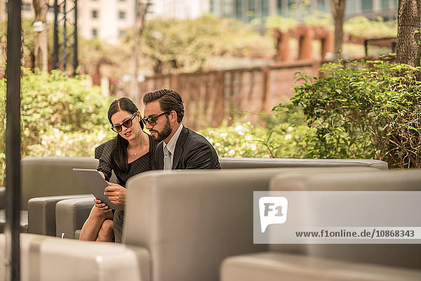 Geschäftsmann und -frau benutzen digitales Tablet auf Hotelgartensofa  Dubai  Vereinigte Arabische Emirate