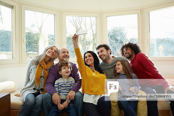 Mehrgenerationen-Familie am Fensterplatz mit Smartphone zum Selbstfahren
