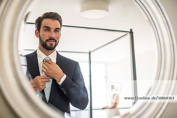 Spiegelbild eines jungen Geschäftsmannes  der Hemd und Krawatte im Hotelzimmer anpasst  Dubai  Vereinigte Arabische Emirate