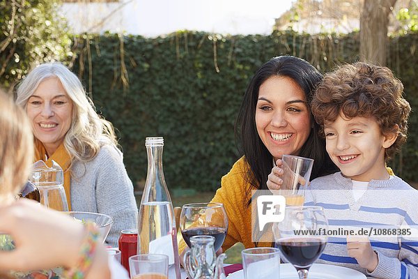 Mehrgenerationen-Familie speist im Freien  lächelnd