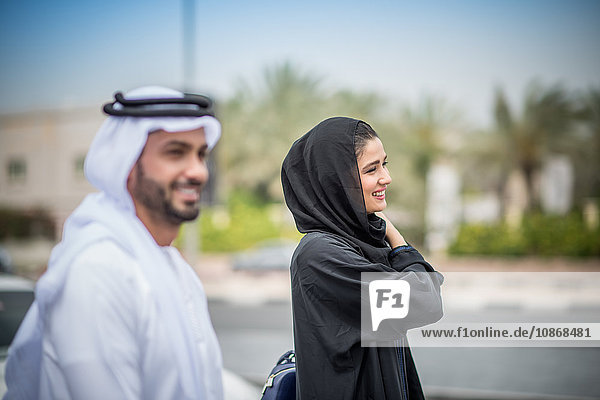 Middle eastern couple wearing traditional clothing walking along street  Dubai  United Arab Emirates