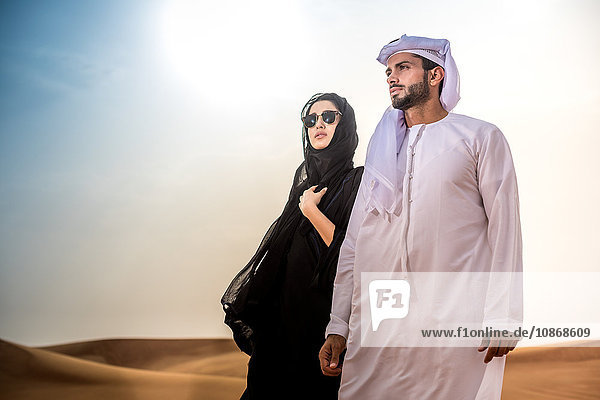 Couple wearing traditional middle eastern clothes in desert  Dubai  United Arab Emirates