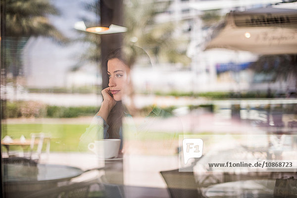 Frau blickt hinter reflektierendes Cafe-Fenster  Dubai  Vereinigte Arabische Emirate