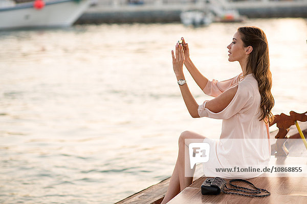 Woman photographing on smartphone on boat at Dubai marina  United Arab Emirates