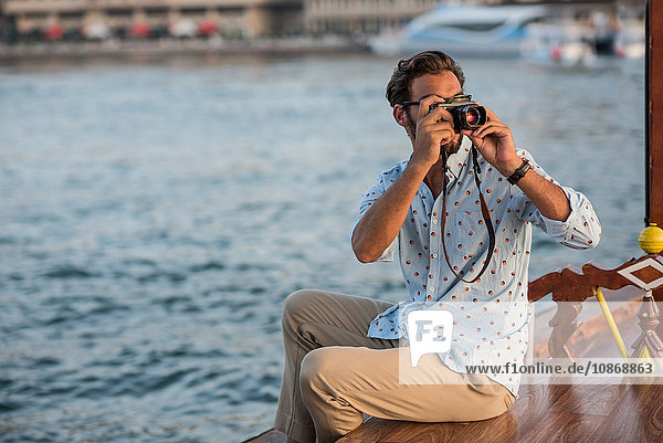 Junger Mann fotografiert vom Boot aus im Yachthafen von Dubai  Vereinigte Arabische Emirate