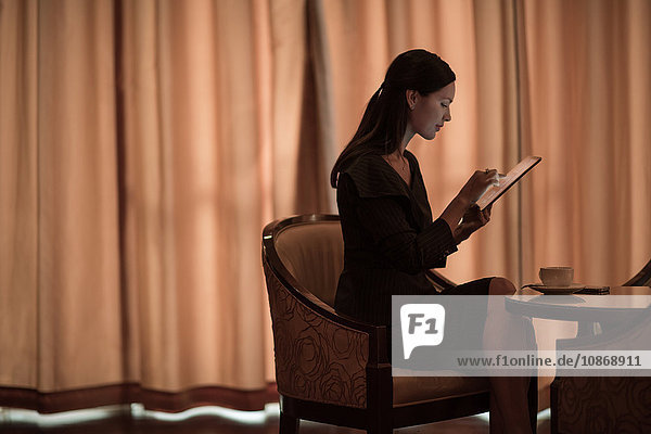 Geschäftsfrau benutzt digitales Tablet am Hoteltisch