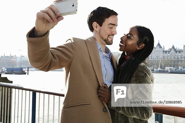 Paar am Fluss stehend  Selbstporträt mit dem Smartphone
