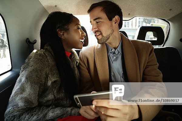 Paar sitzt hinten im Taxi  von Angesicht zu Angesicht  lächelnd