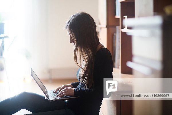 Junge Frau zu Hause  die einen Laptop benutzt