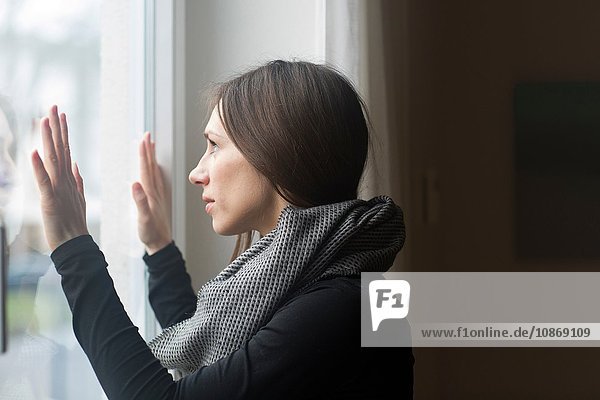 Young woman at home  looking out of window