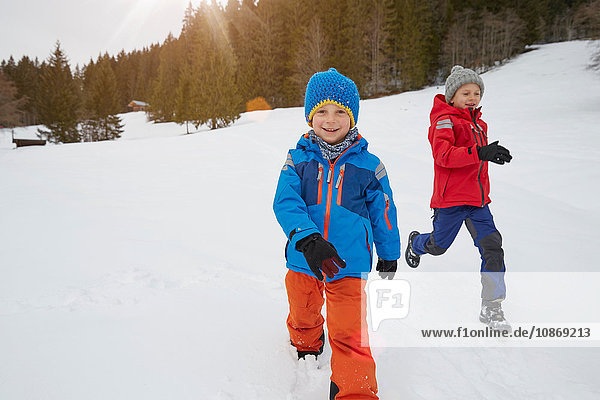 Junge und Bruder laufen in schneebedeckter Landschaft  Elmau  Bayern  Deutschland