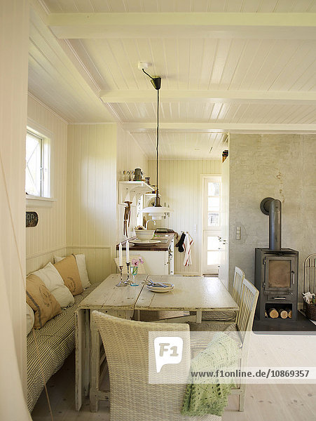 Weiß getäfeltes Wohnzimmer mit Esstisch und Holzofen