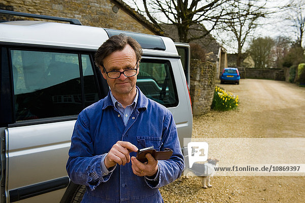 Porträt eines Landwirts vor dem Bauernhaus Text auf Smartphone