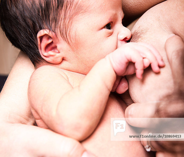 Close up of baby boy breastfeeding from mid adult mother