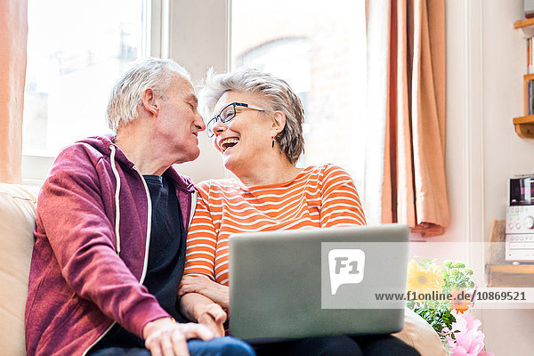 Älteres Ehepaar auf Wohnzimmer-Sofa mit Laptop