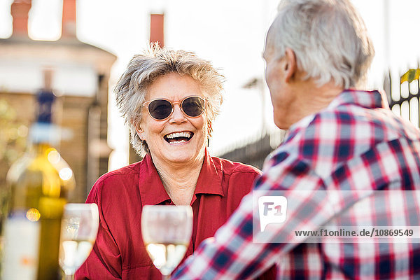 Älteres Ehepaar auf dem Dachgarten der Stadt beim Plaudern und Entspannen mit Weißwein