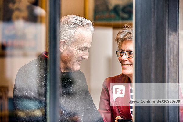 Älteres Ehepaar sitzt am Café-Fensterplatz und plaudert