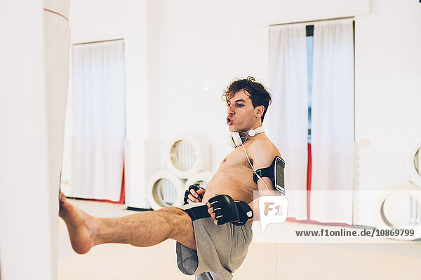 Man in gym wearing heart rate monitor kicking punch bag