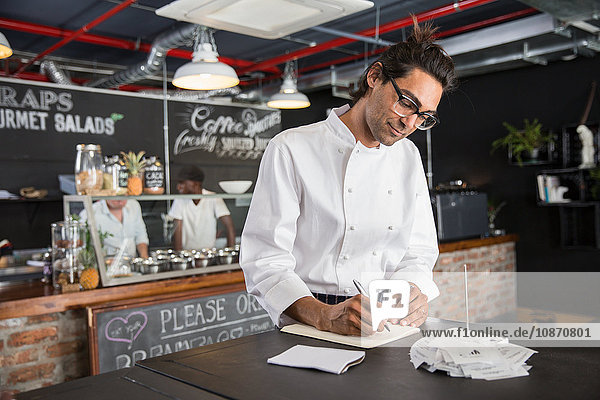 Chef in restaurant writing in notepad