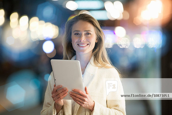 Portrait of businesswoman using digital tablet on city street at night