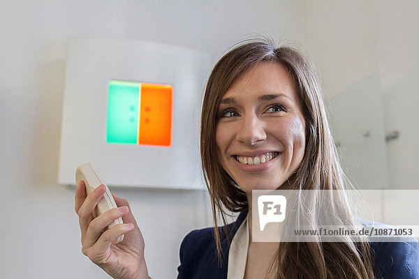 Woman in opticians office holding remote control looking away smiling