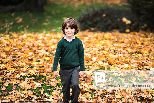 Boy in park in autumn looking at camera smiling