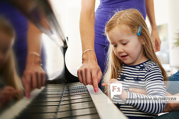 Parents teaching daughter to play piano