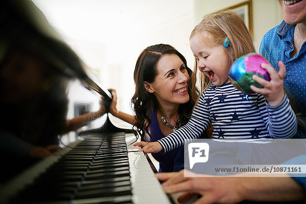 Parents teaching daughter to play piano