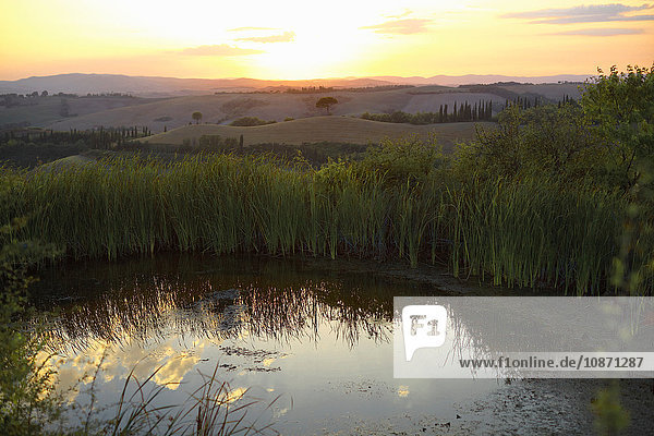 Teich und entfernte Hügellandschaft bei Sonnenaufgang  Toskana  Italien