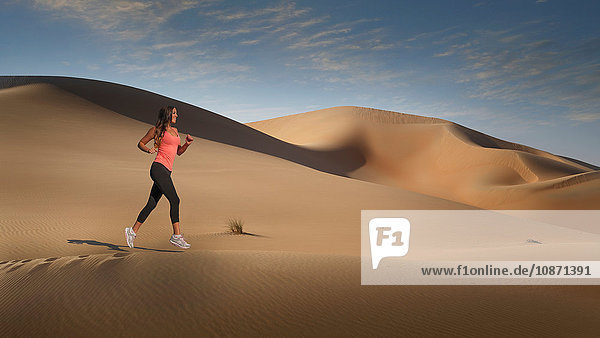 Woman jogging on desert sand dune  Empty Quarter Desert  Abu Dhabi  United Arab Emirates