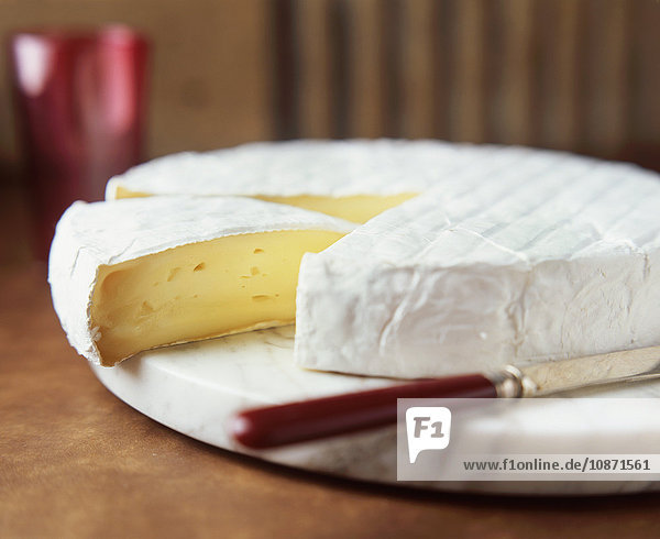 Brie rund mit Käsemesser auf Marmorschneidebrett