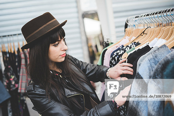 Young woman browsing clothes at market