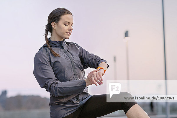 Young woman  wearing sports clothing  looking at activity tracker