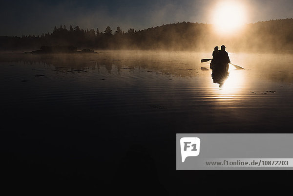 Älteres Ehepaar beim Kanufahren auf dem See bei Sonnenuntergang